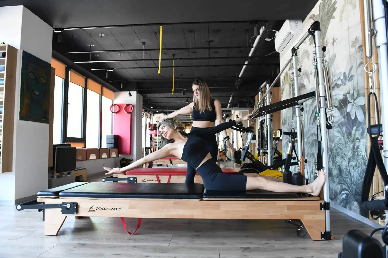 Instructoare care corectează postura unei cursante pe Reformer, în studioul Venusao