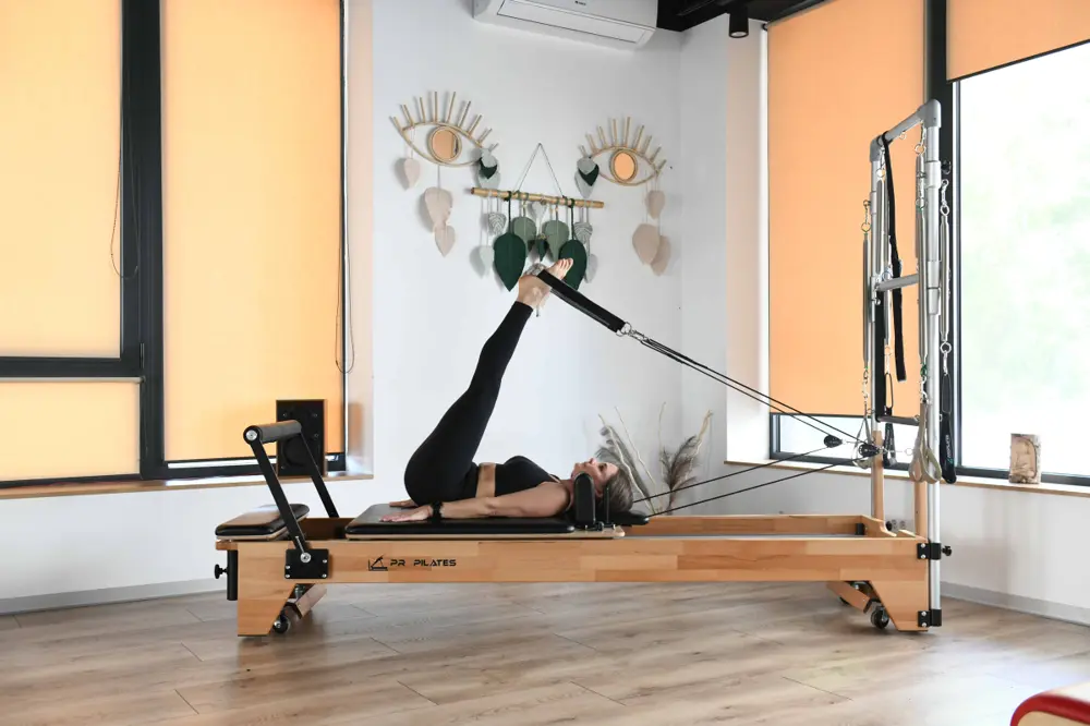 Cursantă care lucrează pe Reformer cu turn, în sala privată a studioului Venusao